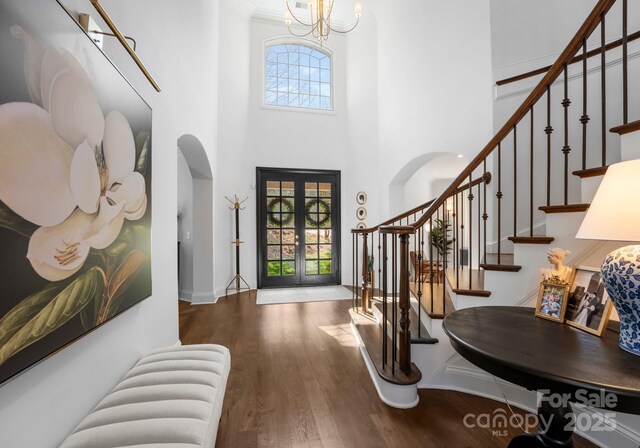 entryway featuring plenty of natural light, arched walkways, a high ceiling, and wood finished floors