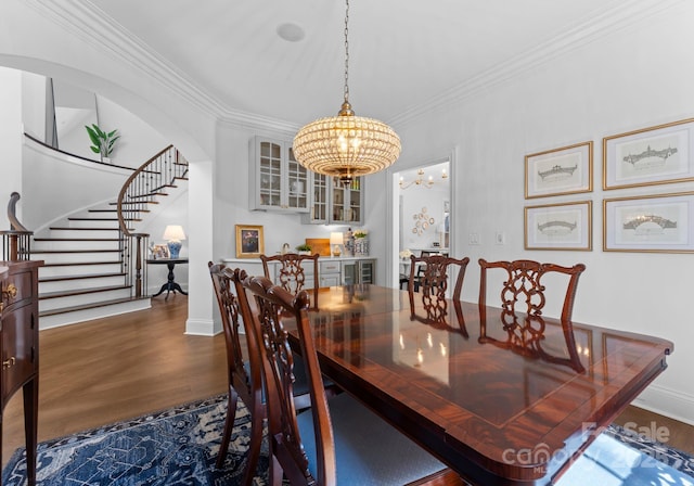 dining area with crown molding, wood finished floors, baseboards, a chandelier, and stairs