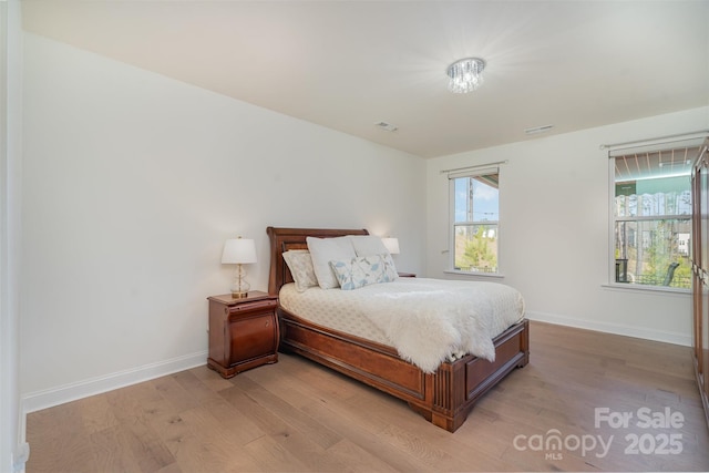 bedroom featuring light wood finished floors, baseboards, and visible vents