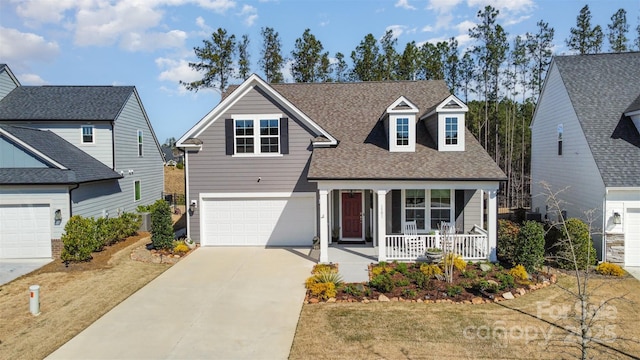 traditional home featuring a garage, concrete driveway, a porch, and roof with shingles