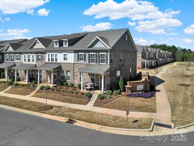 townhome / multi-family property featuring stone siding, a residential view, a porch, and board and batten siding