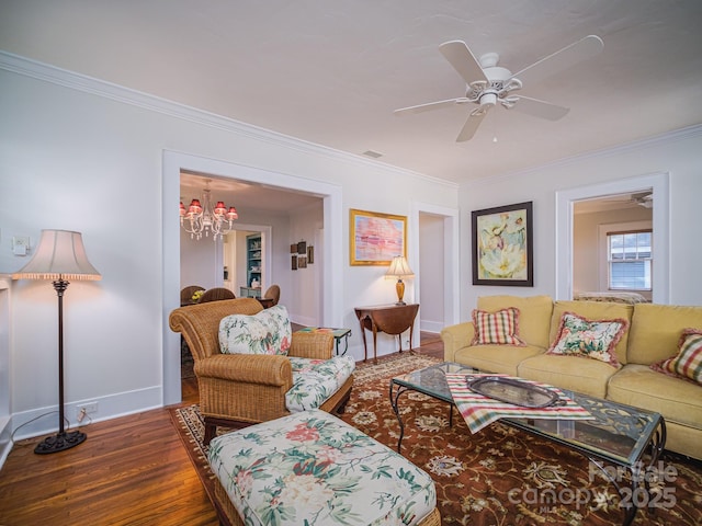 living area with wood finished floors, baseboards, ceiling fan with notable chandelier, visible vents, and ornamental molding