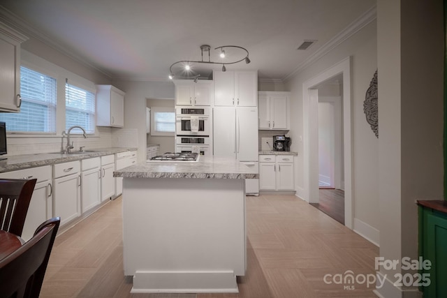 kitchen featuring tasteful backsplash, white appliances, ornamental molding, a sink, and white cabinets