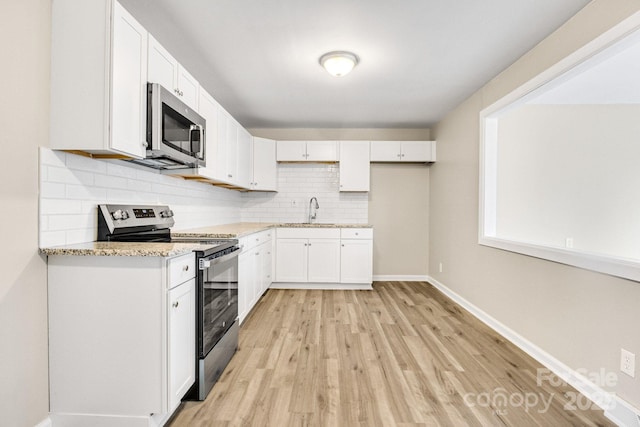 2801 Alleghany St, Charlotte, NC 28208 - kitchen with tasteful backsplash, a sink, light wood-style floors, white cabinets, and appliances with stainless steel finishes