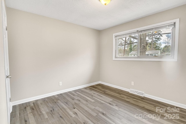 2801 Alleghany St, Charlotte, NC 28208 - spare room with wood finished floors, a textured ceiling, baseboards, and visible vents