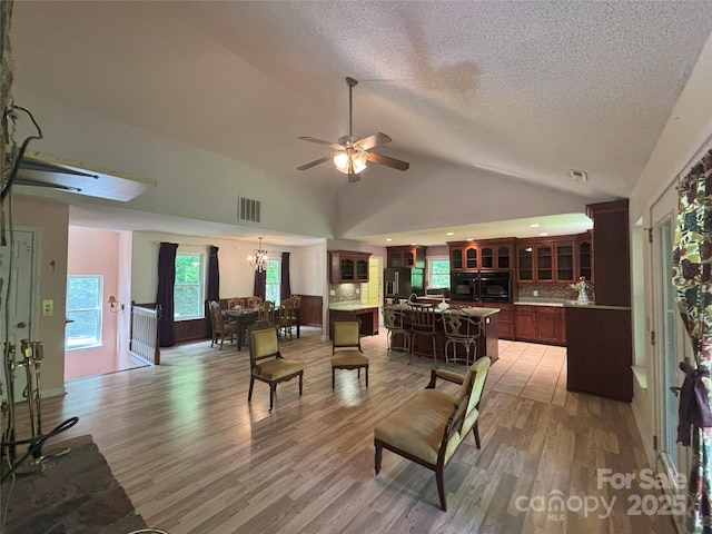 97 Hughes Dr, Maggie Valley, NC 28751 - living room featuring light wood-style floors, lofted ceiling, a textured ceiling, ceiling fan, and a chandelier