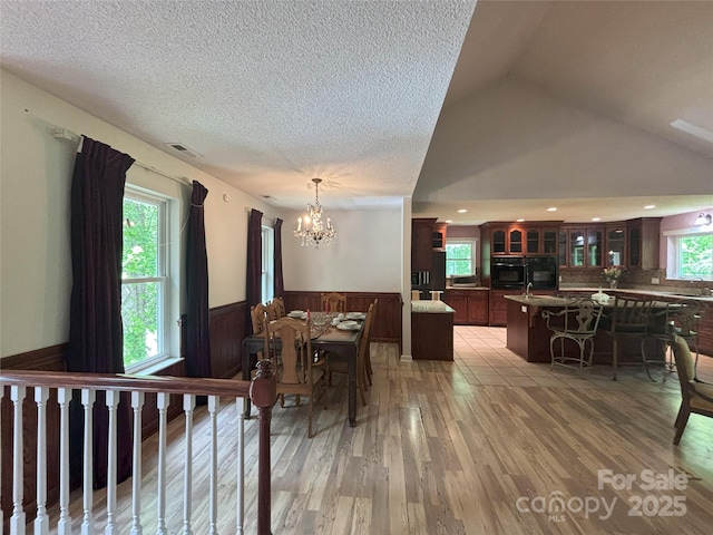 97 Hughes Dr, Maggie Valley, NC 28751 - dining space featuring wainscoting, healthy amount of natural light, a chandelier, light wood finished floors, and a textured ceiling