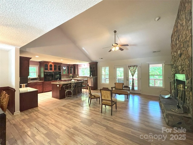97 Hughes Dr, Maggie Valley, NC 28751 - living room with a ceiling fan, light wood-style flooring, a stone fireplace, and high vaulted ceiling
