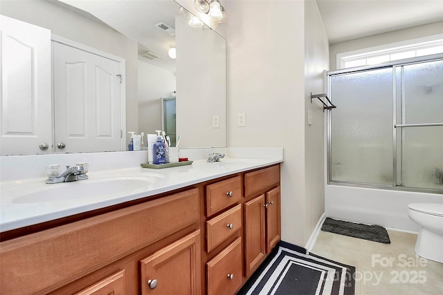7925 Woodmere Dr, Harrisburg, NC 28075 - bathroom with double vanity, toilet, enclosed tub / shower combo, tile patterned floors, and baseboards