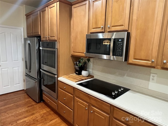 7925 Woodmere Dr, Harrisburg, NC 28075 - kitchen with stainless steel appliances, light countertops, light wood-type flooring, and brown cabinets