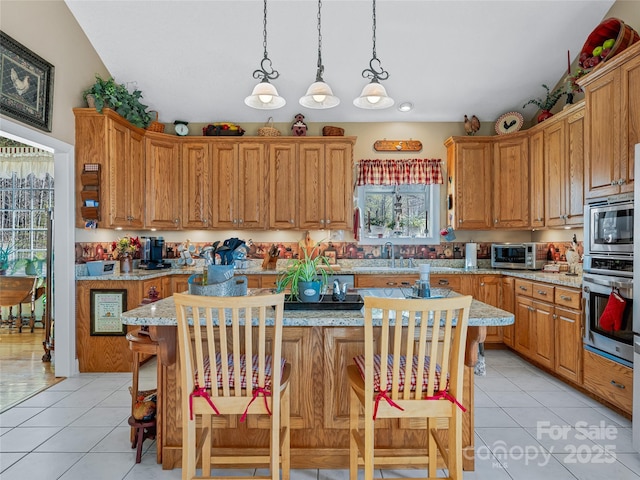 288 Hawks Point Dr, Zirconia, NC 28790 - kitchen featuring a breakfast bar, a center island, light tile patterned floors, stainless steel appliances, and decorative light fixtures