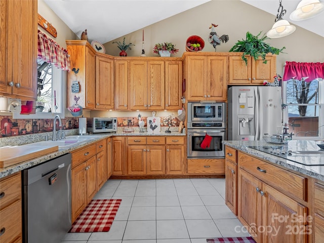 288 Hawks Point Dr, Zirconia, NC 28790 - kitchen with light stone countertops, appliances with stainless steel finishes, lofted ceiling, brown cabinetry, and light tile patterned floors