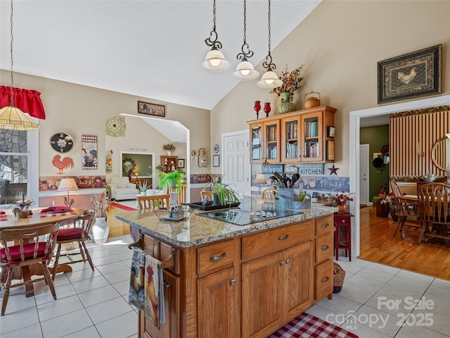 288 Hawks Point Dr, Zirconia, NC 28790 - kitchen with light stone counters, black electric stovetop, brown cabinets, light tile patterned floors, and decorative light fixtures