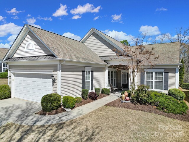 view of front of home featuring a standing seam roof, metal roof, an attached garage, driveway, and a shingled roof