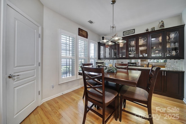dining space with baseboards, visible vents, a notable chandelier, and light wood-style flooring