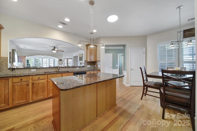 kitchen with a ceiling fan, a kitchen island, arched walkways, and visible vents