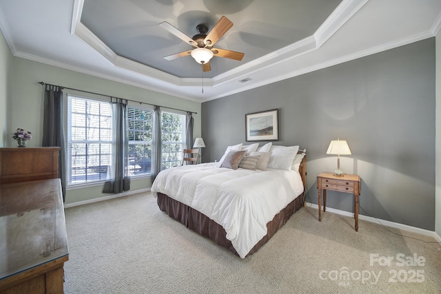 carpeted bedroom with a tray ceiling, baseboards, visible vents, ceiling fan, and ornamental molding