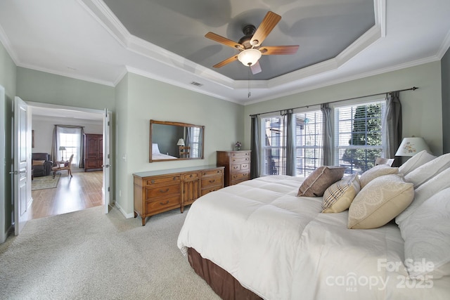 bedroom with light carpet, visible vents, ornamental molding, and a raised ceiling