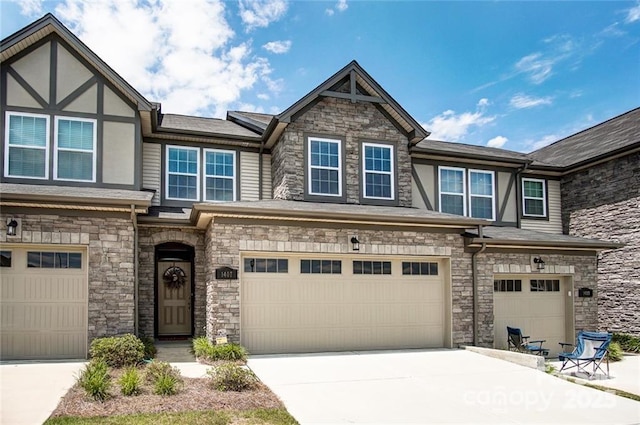 view of front of property with stone siding, an attached garage, and driveway