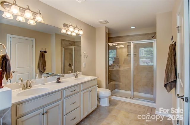 full bath featuring double vanity, a shower stall, tile patterned flooring, and a sink