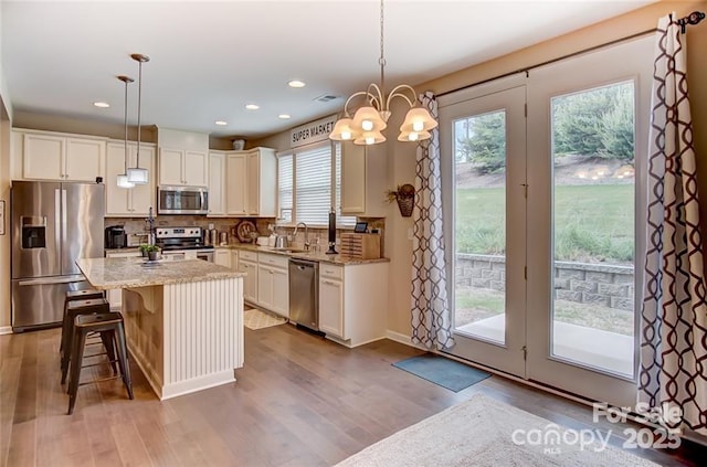 kitchen featuring decorative backsplash, light stone counters, stainless steel appliances, and a sink