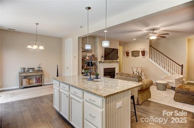 kitchen featuring open floor plan, visible vents, a kitchen island, and dark wood-type flooring