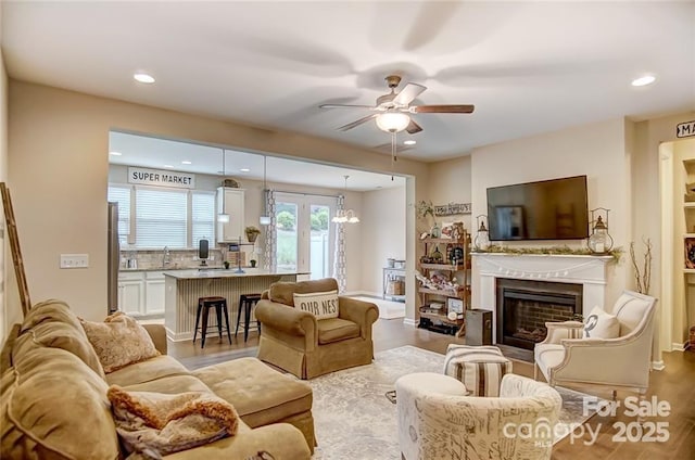 living room with a fireplace, wood finished floors, ceiling fan, and recessed lighting