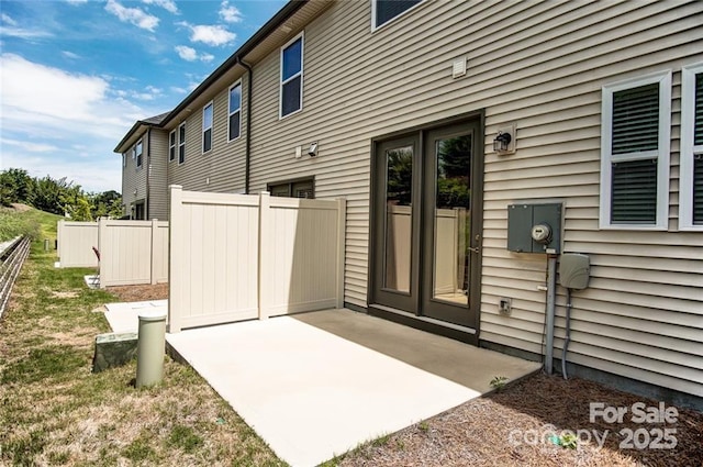 view of exterior entry featuring fence and a patio