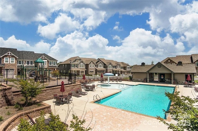 pool with a residential view, a patio, fence, and playground community