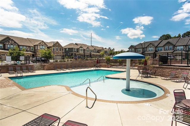 community pool with fence, a residential view, and a patio