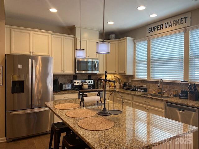 kitchen featuring light stone countertops, a sink, white cabinetry, and appliances with stainless steel finishes