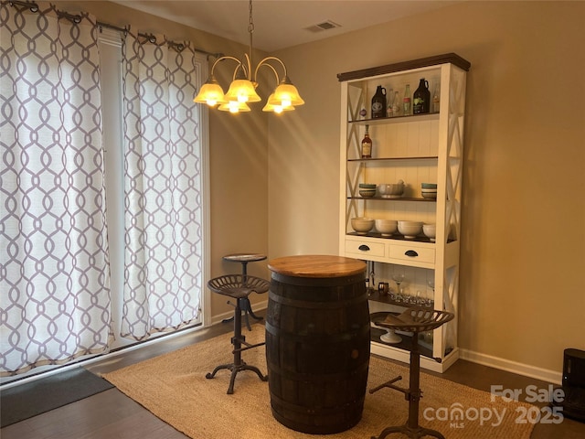 dining area featuring wood finished floors, visible vents, baseboards, and an inviting chandelier