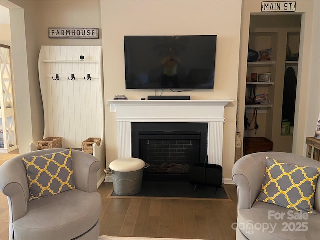 living area with a fireplace with flush hearth and wood finished floors