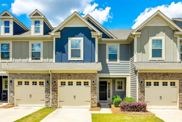 townhome / multi-family property with an attached garage, stone siding, and board and batten siding