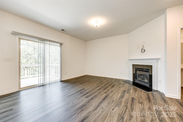 unfurnished living room featuring a glass covered fireplace, baseboards, dark wood-style floors, and visible vents