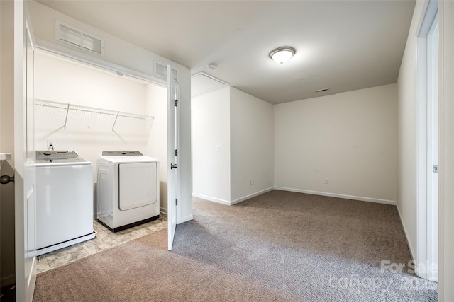 clothes washing area with light carpet, laundry area, visible vents, and washer and clothes dryer
