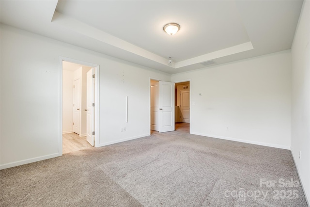 unfurnished bedroom featuring visible vents, baseboards, a raised ceiling, and carpet floors