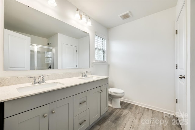 bathroom with a stall shower, visible vents, a sink, and wood finished floors