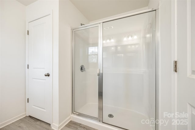 full bathroom with baseboards, wood finished floors, and a stall shower
