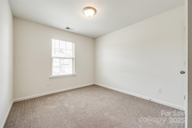 spare room with carpet flooring, visible vents, and baseboards