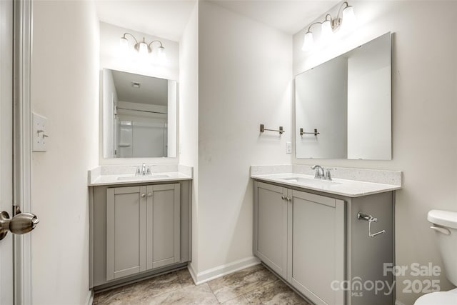 bathroom featuring a sink, toilet, and two vanities