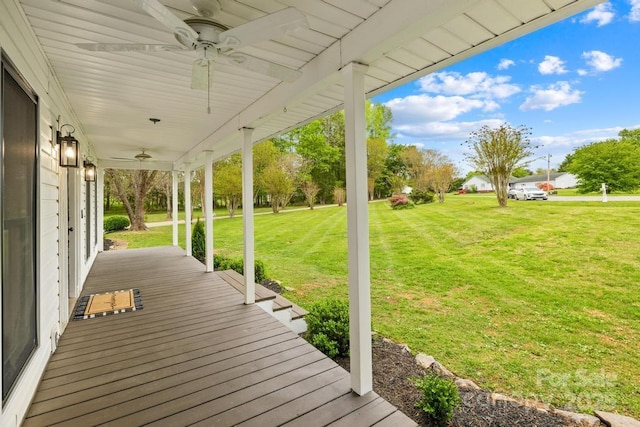 wooden terrace with a porch, a ceiling fan, and a yard