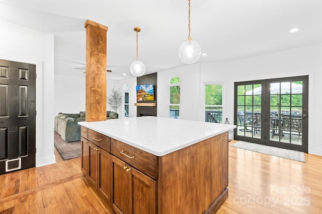 kitchen with recessed lighting, light countertops, light wood-type flooring, a kitchen island, and pendant lighting