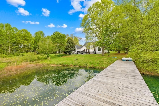 view of dock featuring a lawn and a water view