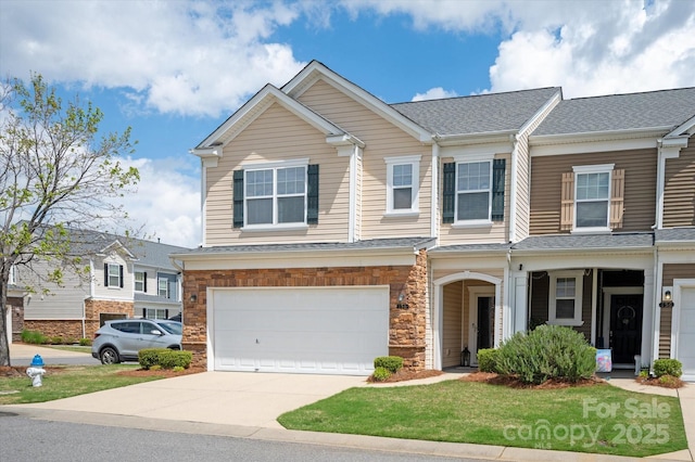 view of front of home with a shingled roof, a front lawn, an attached garage, driveway, and stone siding