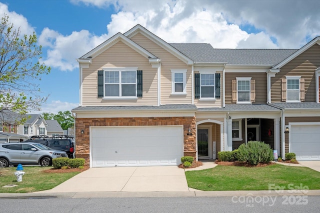 view of front of home with an attached garage, driveway, stone siding, and a shingled roof