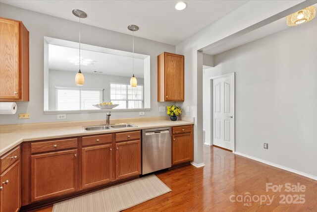 kitchen featuring a sink, wood finished floors, pendant lighting, brown cabinets, and dishwasher