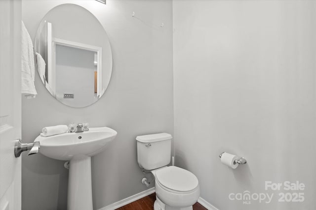 half bath with wood finished floors, toilet, and baseboards