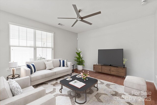 living room featuring ceiling fan, baseboards, wood finished floors, and visible vents