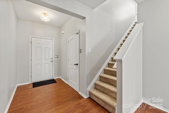entryway featuring baseboards, wood finished floors, and stairway